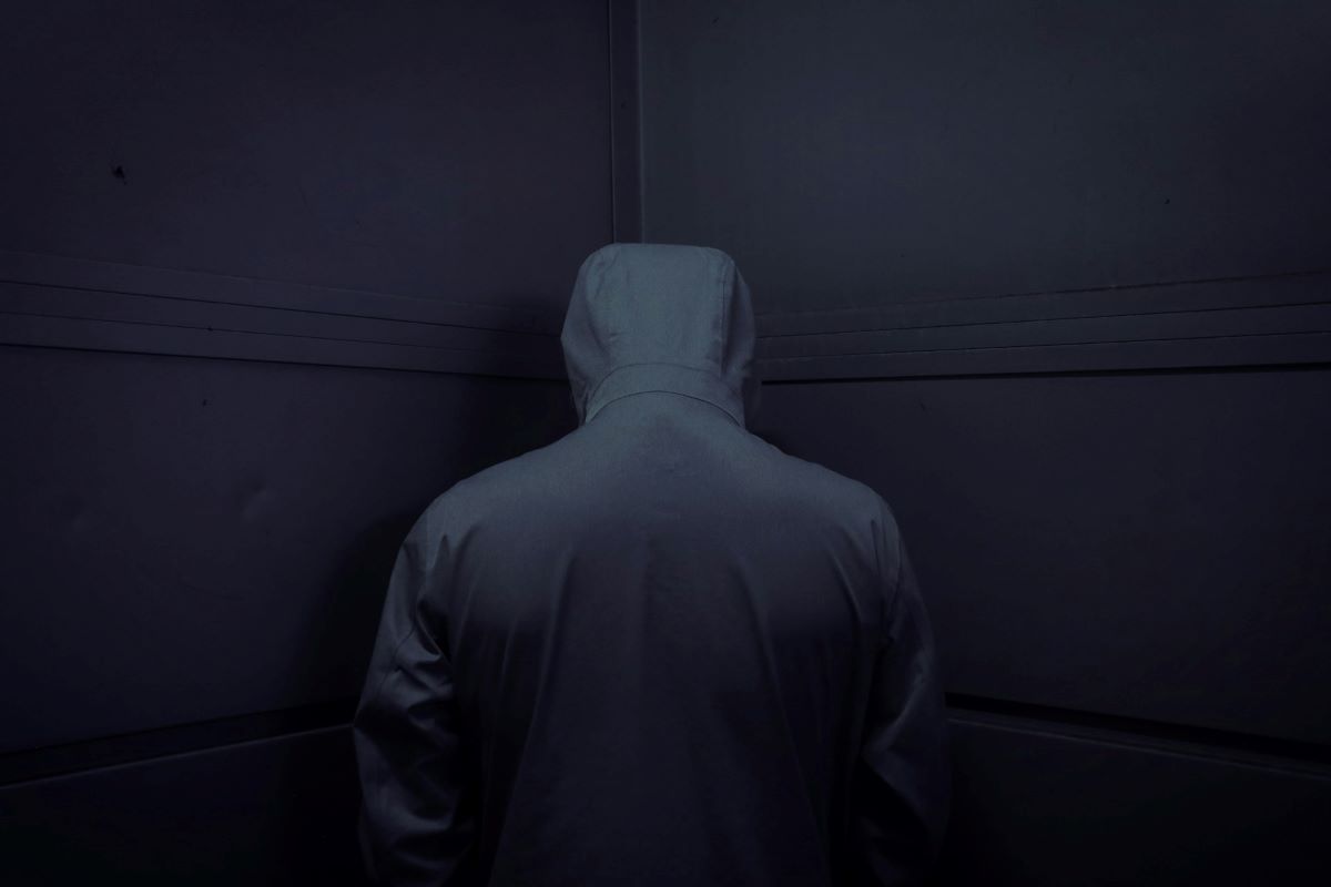 A back photo of a man in a hoodie, an introduction of the common reasons of theft.
